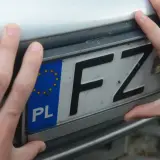 Dłonie trzymają polską tablicę rejestracyjną z literami FZ.