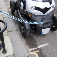 Mały, biały pojazd elektryczny z niebieskim kablem zabezpieczającym. Czy smartem można jeździć bez prawa jazdy? To zależy od modelu i przepisów.