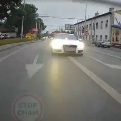 Białe Audi S7 z włączonymi światłami i sygnałem świetlnym jedzie ulicą. Kierowca tego auta prawdopodobnie spieszy się na interwencję.