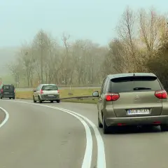 Samochody na mglistej drodze. Myśląc o tym, jak wyrobić prawo jazdy, warto pamiętać o ostrożności na zakrętach.