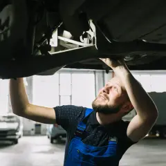 Mechanik sprawdza podwozie auta, szukając rozwiązań jak zwiększyć prześwit w samochodzie.