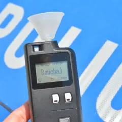 Alkomat z ustnikiem gotowy do pomiaru. Ekran pokazuje "Dmuchaj", wyjaśniając jak działa alkomat.