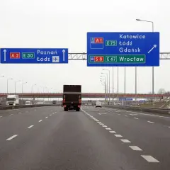 Autostrada z niebieskimi znakami drogowymi wskazującymi kierunki: Poznań, Łódź, Katowice, Gdańsk, Wrocław.