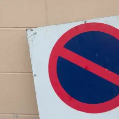 Znak zakaz postoju na tle beżowej ściany.