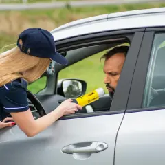 Policjantka bada alkomatem kierowcę. To jeden z przypadków, kiedy policja może badać alkomatem.