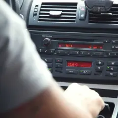 Ręka kierowcy manipuluje przy radiu BMW, pokazując jak ustawić radio w samochodzie. Widoczna temperatura 22°C.