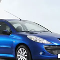 Niebieski Peugeot 206 1.1 stoi na tle nowoczesnej architektury.