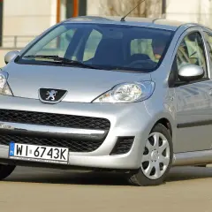 Srebrny Peugeot 107 z przodu, widoczny kierowca.