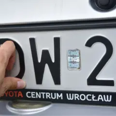 Dłoń poprawia hologram na tablicy rejestracyjnej DW 29. Toyota Centrum Wrocław.