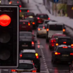 Czerwone światło sygnalizatora, kolejka samochodów. Uważaj, bo za przejazd na czerwonym grozi mandat.