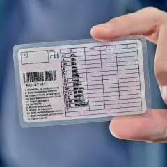Dłoń trzyma polskie prawo jazdy, na którym widnieje numer N0147141. Dokument zawiera informacje o kategoriach pojazdów i datach ważności, kluczowych dla przedłużenia prawa jazdy.