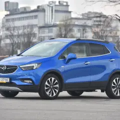 Niebieski Opel Mokka stoi na drodze, w tle budynki i drzewa.