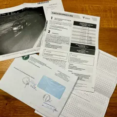 Dokumenty dotyczące wykroczenia drogowego i informacji, jak przedłużyć kartę kierowcy. Widoczny jest raport z fotoradaru, formularz informacyjny oraz koperta.