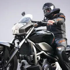 Motocyklista w kasku i kombinezonie na czarnym motocyklu. Zastanawiasz się, jakie prawo jazdy na motor będzie potrzebne?