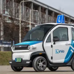 Mały, biało-niebieski pojazd samochodowy inny niż typowe auto, z literą "L" na dachu, idealny do nauki jazdy.