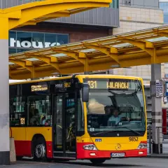 Żółto-czerwony autobus miejski na przystanku. Kierowca autobusu PKS, jak i jego zarobki, to temat dyskusji, ale ten pojazd wozi pasażerów.