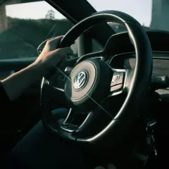 Ręka na kierownicy Volkswagena, na desce rozdzielczej widać prędkość 128 km/h. Zastanawiasz się, czy można sprzedać samochód z miękkim dowodem?