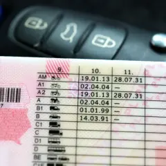 Zbliżenie na polskie prawo jazdy z datami ważności kategorii, obok kluczyki samochodowe. Sprawdź, prawo jazdy na ile lat jest ważne.