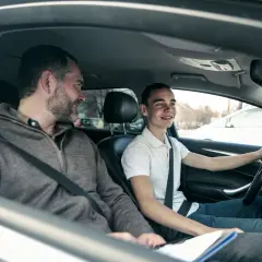 Mężczyzna uczy młodego kierowcę jazdy samochodem.