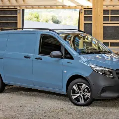 Niebieski Mercedes Vito stoi na żwirowym podłożu, w tle drewniana konstrukcja.