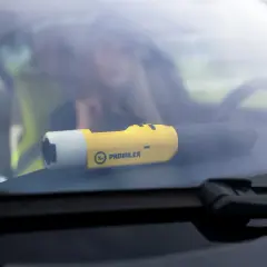 Żółty alkomat Promiler leży na desce rozdzielczej samochodu.