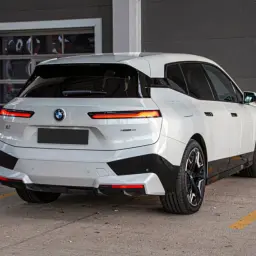Białe BMW iX z czarnymi akcentami stoi na parkingu.
