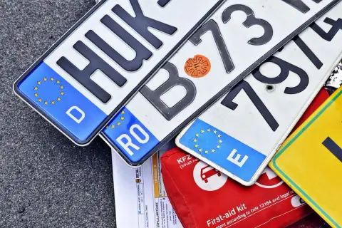 Niemieckie, rumuńskie i inne tablice rejestracyjne państw UE leżą obok apteczki.