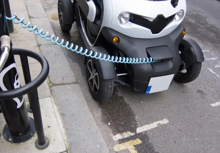 Mały, biały pojazd elektryczny z niebieskim kablem zabezpieczającym. Czy smartem można jeździć bez prawa jazdy? To zależy od modelu i przepisów.