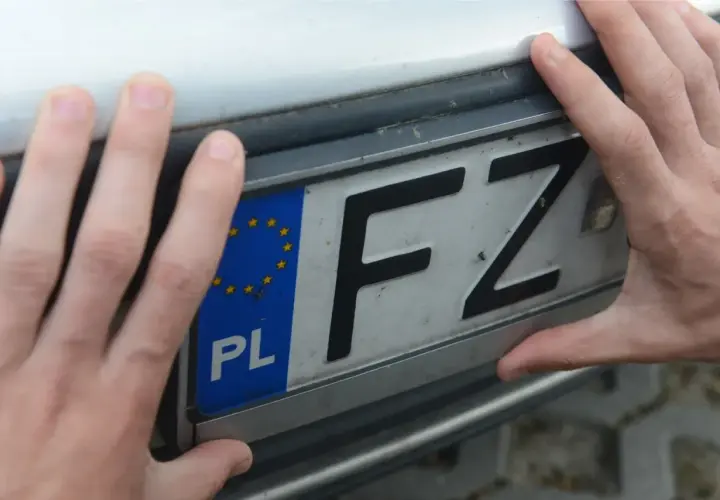 Dłonie trzymają polską tablicę rejestracyjną z literami FZ.