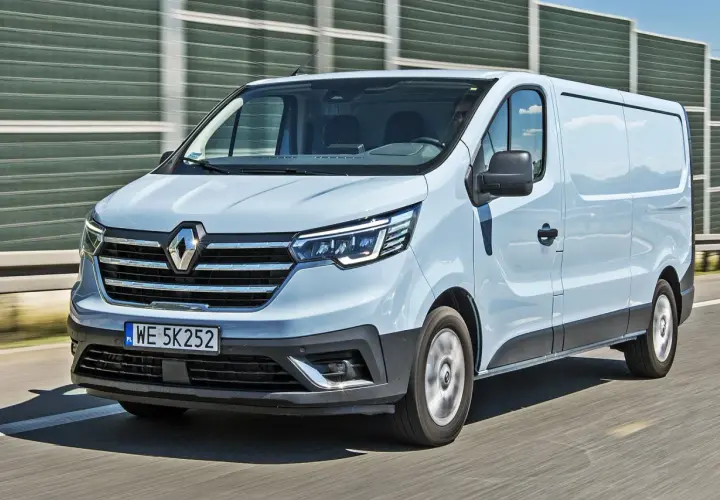 Jasnoszary Renault Trafic 2.0 na drodze, z widocznym przodem i bokiem pojazdu.