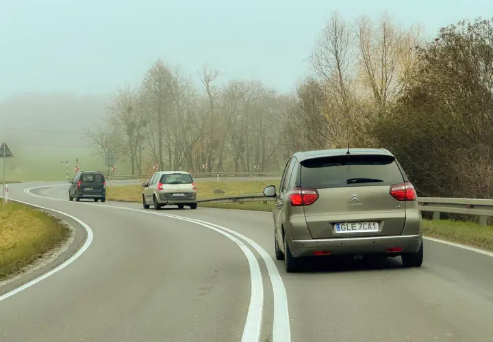 Samochody na mglistej drodze. Myśląc o tym, jak wyrobić prawo jazdy, warto pamiętać o ostrożności na zakrętach.
