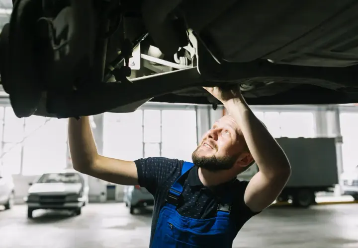 Mechanik sprawdza podwozie auta, szukając rozwiązań jak zwiększyć prześwit w samochodzie.