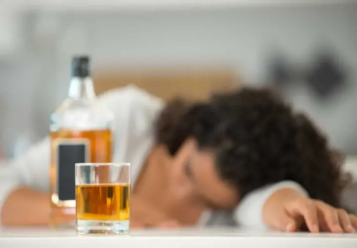 Szklanka z alkoholem i butelka obok śpiącej osoby. Nie ma sposobu, jak sprawdzić promile bez alkomatu.