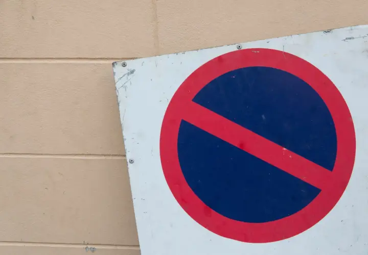 Znak zakaz postoju na tle beżowej ściany.