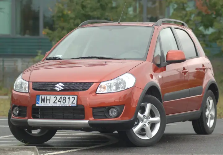 Pomarańczowy Suzuki SX4 z przodu, z widoczną tablicą rejestracyjną.