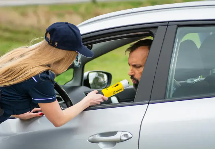Policjantka bada alkomatem kierowcę. To jeden z przypadków, kiedy policja może badać alkomatem.