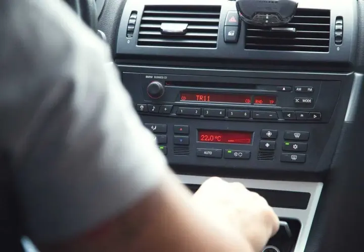 Ręka kierowcy manipuluje przy radiu BMW, pokazując jak ustawić radio w samochodzie. Widoczna temperatura 22°C.