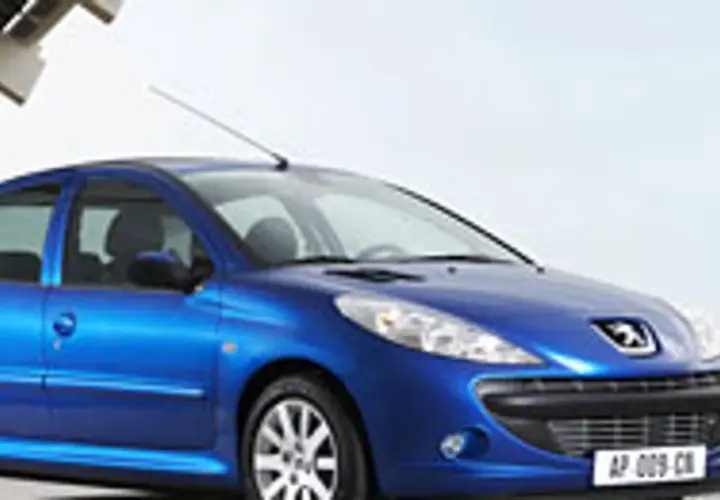 Niebieski Peugeot 206 1.1 stoi na tle nowoczesnej architektury.