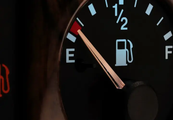 Wskaźnik paliwa w Toyocie Yaris pokazuje niski poziom. Czerwona lampka ostrzegawcza z ikoną dystrybutora paliwa świeci się, a wskazówka na wskaźniku znajduje się blisko litery "E", sygnalizując niski **pojemność baku**.