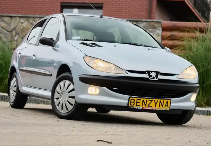 Jasny Peugeot 206 1.4 benzyna z żółtą tablicą rejestracyjną "BENZYNA" stoi na zewnątrz.
