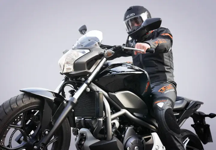 Motocyklista w kasku i kombinezonie na czarnym motocyklu. Zastanawiasz się, jakie prawo jazdy na motor będzie potrzebne?