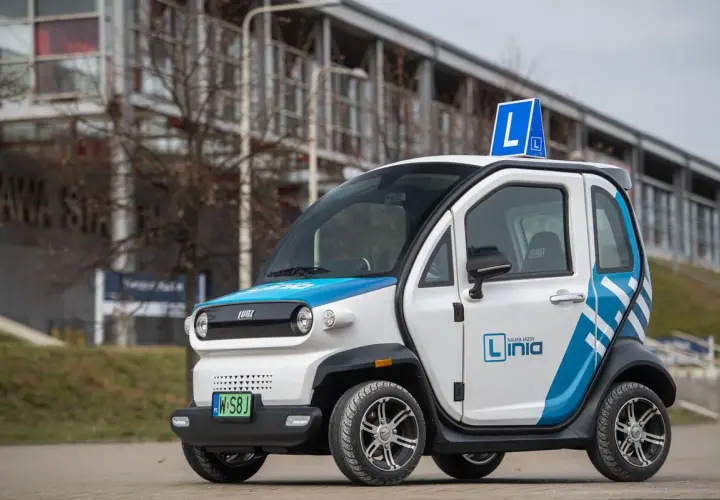 Mały, biało-niebieski pojazd samochodowy inny niż typowe auto, z literą "L" na dachu, idealny do nauki jazdy.