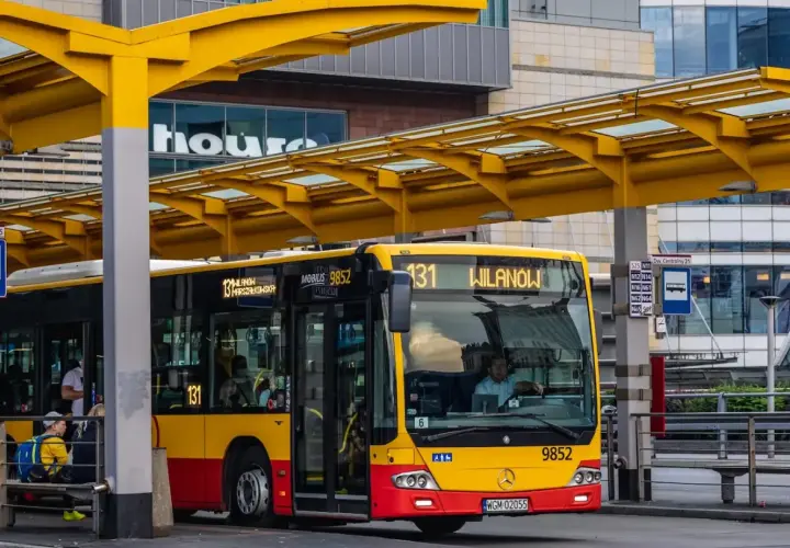 Żółto-czerwony autobus miejski na przystanku. Kierowca autobusu PKS, jak i jego zarobki, to temat dyskusji, ale ten pojazd wozi pasażerów.