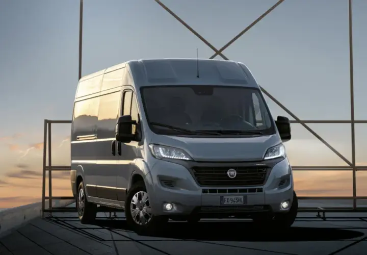 Szary Fiat Ducato na tle zachodzącego słońca. Zastanawiasz się nad pojemnością baku? Ten model oferuje duży zasięg.