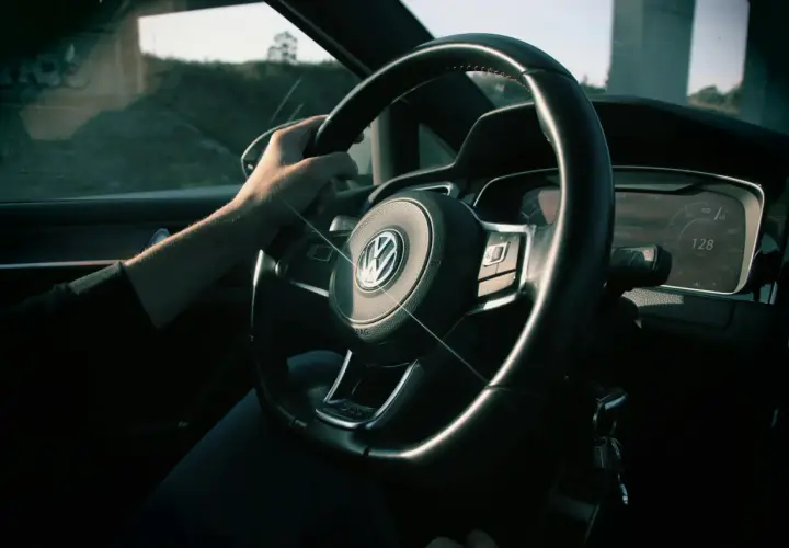 Ręka na kierownicy Volkswagena, na desce rozdzielczej widać prędkość 128 km/h. Zastanawiasz się, czy można sprzedać samochód z miękkim dowodem?