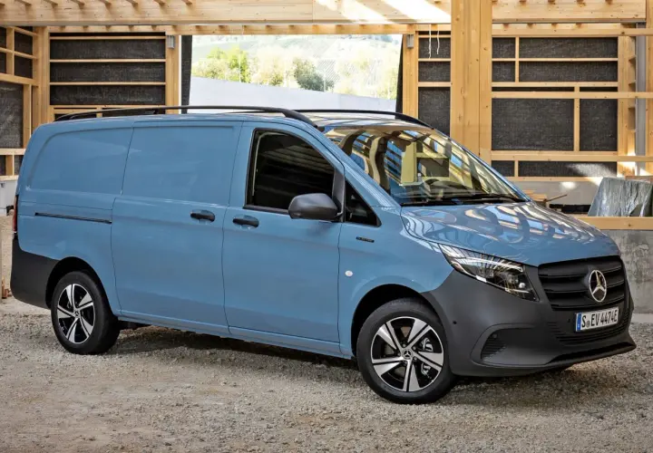 Niebieski Mercedes Vito stoi na żwirowym podłożu, w tle drewniana konstrukcja.
