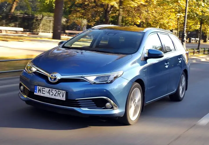 Niebieska Toyota Auris Hybrid kombi w ruchu ulicznym, jesienią.