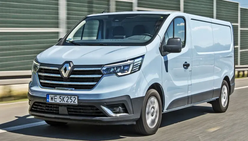 Jasnoszary Renault Trafic 2.0 na drodze, z widocznym przodem i bokiem pojazdu.
