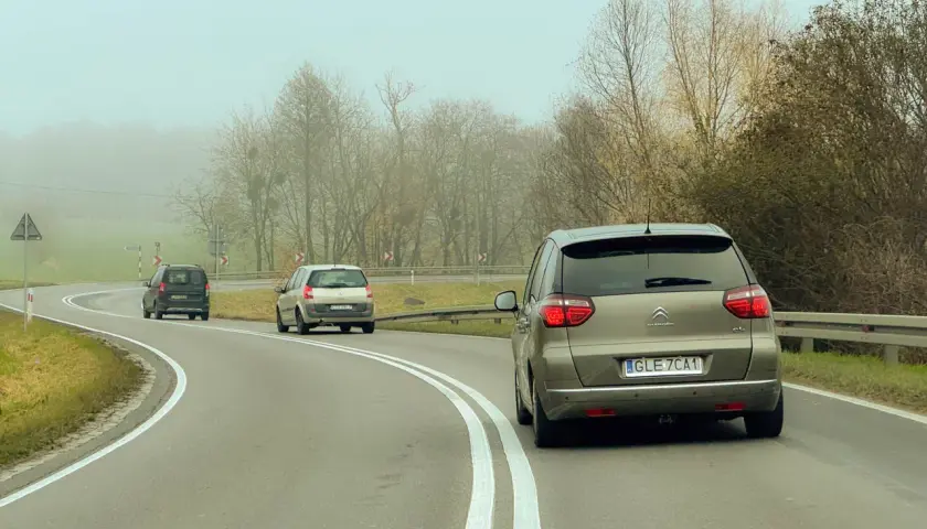 Samochody na mglistej drodze. Myśląc o tym, jak wyrobić prawo jazdy, warto pamiętać o ostrożności na zakrętach.
