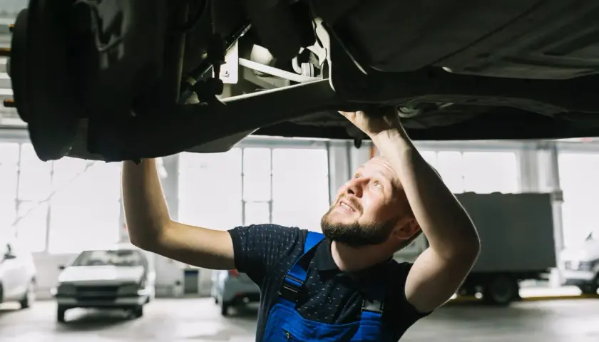 Mechanik sprawdza podwozie auta, szukając rozwiązań jak zwiększyć prześwit w samochodzie.